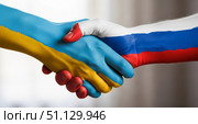 Рукопожатие мира с флагами Украины и России на руках. Стоковое AI-изображение, AI-художник Журавлева Кристина / Фотобанк Лори