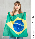 Sad young woman holding flag of Brazil against unicoloured background. Стоковое фото, фотограф Яков Филимонов / Фотобанк Лори