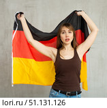 Sad young woman holding flag of Germany against unicoloured background. Стоковое фото, фотограф Яков Филимонов / Фотобанк Лори