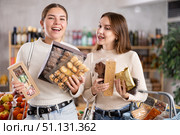 Two girls in store while shopping, choose sweets and chat sweetly. Стоковое фото, фотограф Яков Филимонов / Фотобанк Лори