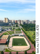 St. Petersburg, Russia - A football green field and stadium in the hockey city of St. Petersburg, surrounded by green forest and city street. Aerial view, vertical shot. Редакционное фото, фотограф Ирина Михайличенко / Фотобанк Лори