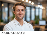 Confident Young Professional Smiling in Modern Office Space with Soft Lighting and Minimalist Decor, Capturing the Essence of Productive Work Environment. Стоковое AI-изображение, AI-художник Башкирова Анна / Фотобанк Лори