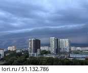 Dark, heavy clouds hang low over a modern city with residential buildings and green trees. Concept of: Impending weather. Стоковое фото, фотограф Ольга Петрова-Апостолова / Фотобанк Лори