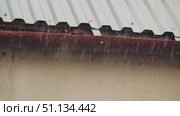 A close-up of a metal roof over which torrential rain flows down into a storm drain. Slow motion shooting of rain. Стоковое видео, видеограф Воловодов Владимир / Фотобанк Лори