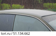 A close-up of the roof and side windows of a car with raindrops beating on them. Slow motion of rain. Water running down the windows and body of the car. A cloudy spring day. Стоковое видео, видеограф Воловодов Владимир / Фотобанк Лори
