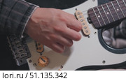 Close-up of a hand strumming an electric guitar. Pickups and volume control. The guitarist has a checkered shirt sleeve. Стоковое видео, видеограф Воловодов Владимир / Фотобанк Лори