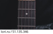 Close-up of a dark rosewood electric guitar fingerboard, highlighting the metal fret and single dot marker. Black leather background. Стоковое видео, видеограф Воловодов Владимир / Фотобанк Лори