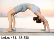 Portrait of caucasian experienced woman yoga teacher performs ardha chakrasana on seashore at sunset. Стоковое фото, фотограф Яков Филимонов / Фотобанк Лори