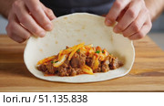 Professional chef creating gourmet taco, expertly wrapping soft tortilla with seasoned ground beef and kimchi on rustic wooden cutting board. Стоковое AI-видео, аниматор Юрий Поздников / Фотобанк Лори