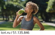 Fit woman drinking green smoothie near trees, recovering after high intensity training, representing athletic lifestyle and natural health rejuvenation. Стоковое AI-видео, аниматор Юрий Поздников / Фотобанк Лори