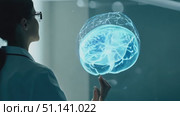 A researcher analyzes a glowing holographic brain displayed in a high-tech laboratory setting. Стоковое AI-видео, аниматор Данила Большаков / Фотобанк Лори