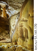 Dark cave view from inside with a lumen. Stalactites and stalagmites inside the stone grotto. Colorful stones in the cave. Lighting electricity beauty of the cave. (2019 год). Стоковое фото, фотограф Наталия Кирсанова / Фотобанк Лори