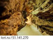 Dark cave view from inside with a lumen. Stalactites and stalagmites inside the stone grotto. Colorful stones in the cave. Lighting electricity beauty of the cave. (2019 год). Стоковое фото, фотограф Наталия Кирсанова / Фотобанк Лори