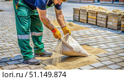 Construction Worker Pouring Sand Between Pave rs on a City Street. Generative AI. Стоковое AI-изображение, AI-художник Roman Zavorotny / Фотобанк Лори