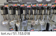 Shop windows with kitchen utensils. The stand displays skimmers, spoons, ladles, spatulas, potato mashers and other cooking accessories in neat rows. All products are made in a modern style - with metal working parts and comfortable handles, some elements have rubberized inserts for a comfortable grip. Each item has price tags indicating discounts and special offers. The assortment is presented in a single style, which creates a neat and attractive look of the showcase. Such a photo is suitable for illustrations in online stores, kitchen goods catalogs, articles about cooking and household accessories. Редакционное фото, фотограф Анна Кривицкая / Фотобанк Лори