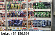 Supermarket display cases with a wide range of yogurts and fermented milk products. The shelves feature various brands and flavors: fruit, natural, low-fat, and high-protein. The packaging in different colors — green, white, blue, and bright designer ones — attracts the attention of customers. The products are arranged in rows in a refrigerated display case with price tags and promotional offers. The photo shows a modern store interior, a selection of dairy products, and a healthy eating culture. Редакционное фото, фотограф Анна Кривицкая / Фотобанк Лори