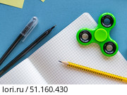 Back to School Supplies with Notebook, Fidget Spinner, Sticky Notes and Pens on Blue Background.Flat lay composition of school supplies on a blue desk. Open squared notebook with pencil, pens, sticky notes, colorful fidget spinner and highlighters. Creative back to school background, education concept, stationery for students and kids. Стоковое фото, фотограф Анастасия Мерчик / Фотобанк Лори