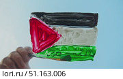 The artist paints the flag of Palestine in bright colors on glass against the background of a serene azure sky, embodying security and serenity. Стоковое видео, видеограф Strunov David / Фотобанк Лори