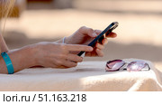 Woman with smartphone on a sun lounger on the beach by the sea. Стоковое фото, фотограф Igor Skripachev / Фотобанк Лори