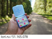 Hand holding daily pill organizer with medical pills in nature. Стоковое фото, фотограф Дмитрий Цветков / Фотобанк Лори