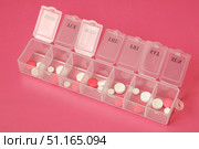 Transparent weekly pill organizer containing various pills on pink background. Стоковое фото, фотограф Дмитрий Цветков / Фотобанк Лори