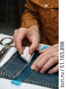 Tailor using chalk to mark hem jeans during alteration process in workshop setting. closeup. Стоковое фото, фотограф ЛУНИНА ВЕРОНИКА / Фотобанк Лори