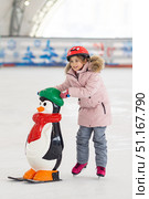 Happy little girl in warm pink coat and red safety helmet holding kids support and learning to skate on ice skating rink. Fall down and have fun. Winter sport, outdoors. Holiday and seasonal concept. Стоковое фото, фотограф Ирина Михайличенко / Фотобанк Лори