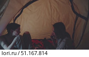Two young women enjoy a relaxing moment inside their tent, chatting, holding hands, and playfully tickling each other's feet, creating a cozy and intimate atmosphere. Стоковое AI-видео, аниматор Юрий Поздников / Фотобанк Лори