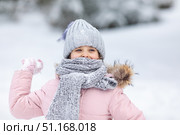 Little girl having fun playing with fresh snow during snowfall. Snowball fight. Kid dressed in warm clothes, hat, hand gloves and scarf. Active outdoors leisure for child on nature in snowy winter day. Стоковое фото, фотограф Ирина Михайличенко / Фотобанк Лори