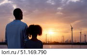 Father and daughter looking at solar panels. Solar farm and sunlight at sunset. Solar energy for green energy. Sustainable renewable energy. Photovoltaic power plant or solar park. Energy sustainability. Стоковое AI-изображение, AI-художник ALLA YURTAYEVA / Фотобанк Лори