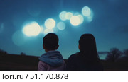 Two children enjoy a peaceful moment, marveling at the full moon's glow in a serene countryside. Стоковое AI-видео, аниматор Данила Большаков / Фотобанк Лори