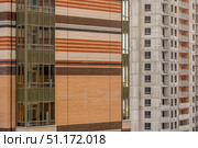 Фасад строящегося многоэтажного дома с кирпичной облицовкой рядом с бетонным каркасом другого здания. Стоковое фото, фотограф Кирилл Сиротюк / Фотобанк Лори