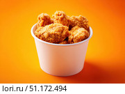 Crispy chicken on a yellow orange color background. Bucket overflowing with golden Fried Chicken Strips. Street food. Coated batter southern style chicken drumsticks and pieces. BBQ Feast. Nuggets. Стоковое AI-изображение, AI-художник Марина Демидюк / Фотобанк Лори