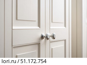 Close-up macro of golden cabinet hardware on white doors. Handle with brass finish. Minimalist simple interior style. Cabinet door double doors with both handles. Furniture base set design. Стоковое AI-изображение, AI-художник Марина Демидюк / Фотобанк Лори