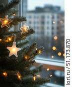 Sparkling Star Ornaments and Warm Lights Adorn a Christmas Tree Indoors During Winter. Стоковое AI-изображение, AI-художник Юлия Гапеенко / Фотобанк Лори