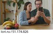 Loving mature couple using mobile phone. Husband and wife hugging, holding hands and looking at the smartphone screen. Man and woman share content on social media app. Young people watch the cellphone. Стоковое видео, видеограф Марина Демидюк / Фотобанк Лори