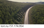 Scenic winding road through lush forest landscape at sunset. Стоковое видео, видеограф Гурьянов Андрей / Фотобанк Лори
