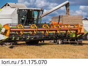 Agricultural machinery. Agricultural industry. A combine harvester picks up golden ears of ripe wheat. The concept of planting and harvesting a bountiful harvest. Стоковое фото, фотограф Photojuli / Фотобанк Лори