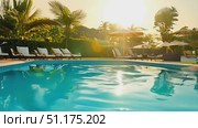 Relax beside a tranquil pool as the sun sets over a tropical escape with palm trees swaying gently. Стоковое AI-видео, аниматор Данила Большаков / Фотобанк Лори