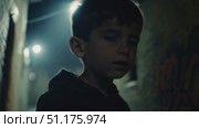 A child stands quietly in a dimly lit alley, looking around as if searching for someone. Стоковое AI-видео, аниматор Данила Большаков / Фотобанк Лори