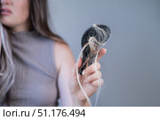 Frustrated woman holding hairbrush with fallen strands showing signs of hair loss and damaged brittle hair. Стоковое фото, фотограф Svetlana Golovco / Фотобанк Лори