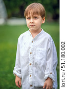 A young handsome boy of European appearance enjoys spending time on the green lawn at home. It's a great time to relax. Стоковое фото, фотограф Алина Лебедь / Фотобанк Лори