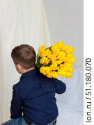 A young, beautiful boy. He carries a huge armful of fresh yellow tulips on his shoulder. The concept of spring and holiday, March 8, International Women's Day. Стоковое фото, фотограф Алина Лебедь / Фотобанк Лори