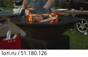 Burger master positions split burger buns on perimeter of circular barbecue, ensuring they are cooked by direct heat of flames. Стоковое видео, видеограф Strunov David / Фотобанк Лори