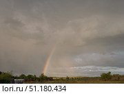 Large beautiful cumulus clouds and rainbow in evening sunset sky above golden field, summer landscape. Стоковое фото, фотограф irisff / Фотобанк Лори