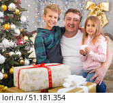 Happy father with son and daughter near the Christmas tree in living room. Merry Christmas. Стоковое фото, фотограф Татьяна Яцевич / Фотобанк Лори