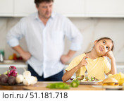 Father forcing little daughter to eat vegetable salad in kitchen. Стоковое фото, фотограф Татьяна Яцевич / Фотобанк Лори