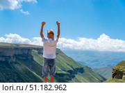 Teenager boy standing on top of mountain with raised hands, looking away with pleasure. School boy hiking in mountains, Мальчик стоит на краю пропасти подняв руки вверх, Тобот, Дагестан. Стоковое фото, фотограф Данила Большаков / Фотобанк Лори