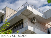View of old building with balconies and terraces to accommodate tourists on vacation against blue sky. Bottom view of terrace of building and external air conditioning unit below it. Стоковое фото, фотограф Данила Большаков / Фотобанк Лори