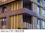 Monolithic concrete frame of apartment building under construction with partially attached facade cladding blocks. Energy efficiency. Installation of external wall thermal insulation with rock wool. Стоковое фото, фотограф Данила Большаков / Фотобанк Лори